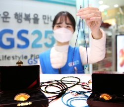 GS25 직원이 황금소코인과 원석마스크스트랩을 두고 포즈를 취하고 있다사진=GS25